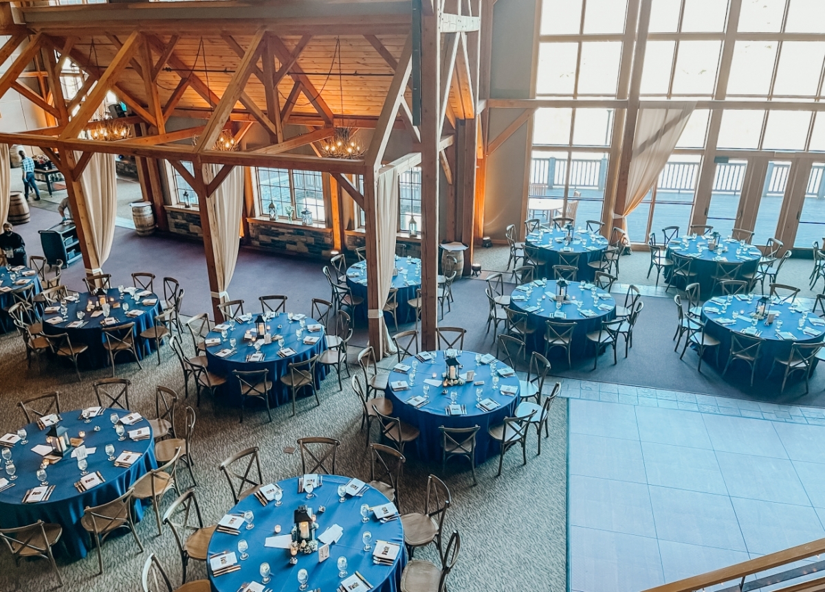 A large room with blue circular tables set for an event